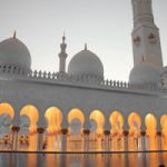 Stunning view of Sheikh Zayed Mosque with illuminated arches and domes during dusk.